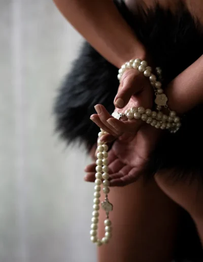 Boudoir detail photograph of hands holding pearl jewellery