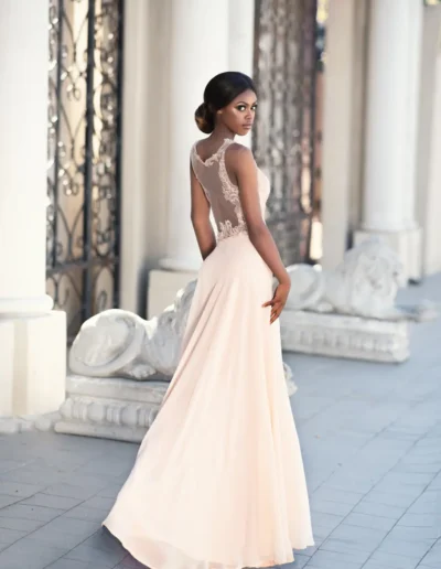 Woman in an elegant blush bridal gown beside classical columns