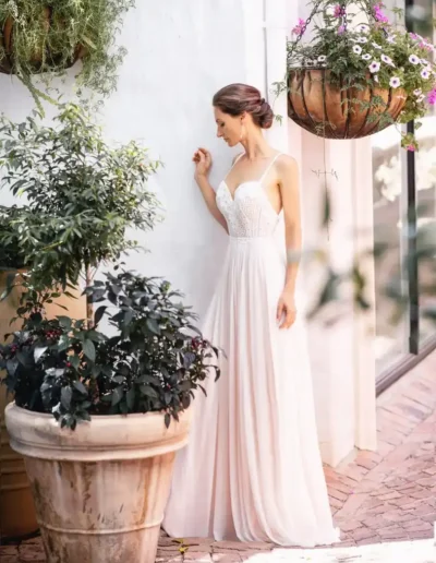 Bride in a lace wedding dress standing among garden flowers
