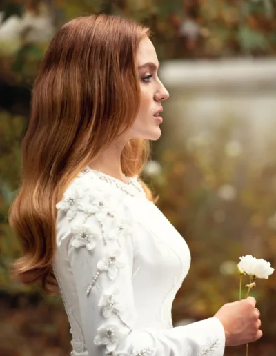 Red-haired bride holding a white flower in an autumn garden