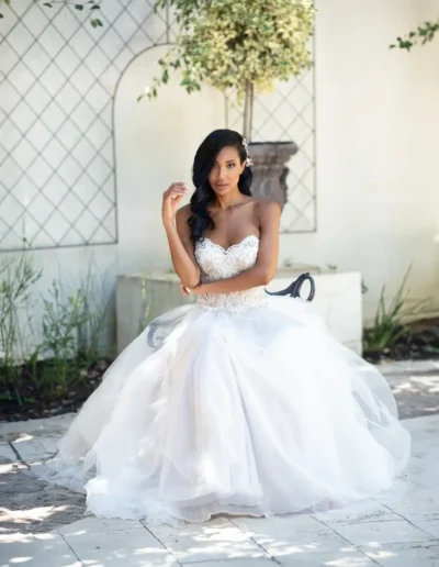Bride in a voluminous white ball gown seated outdoors