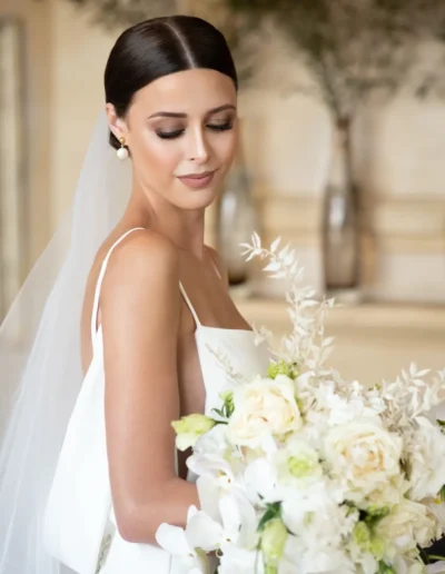 Bride in a fitted lace wedding dress posing beside a garden fountain