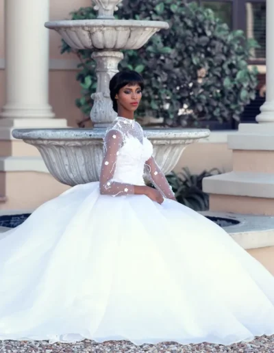 Bride in a layered pink wedding gown standing in a formal garden