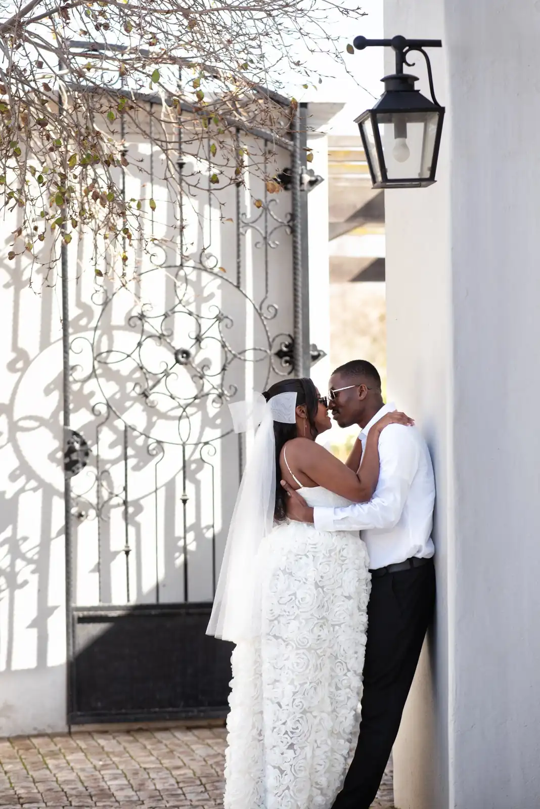 Engaged couple kissing beside an ornate gate in Cape Town