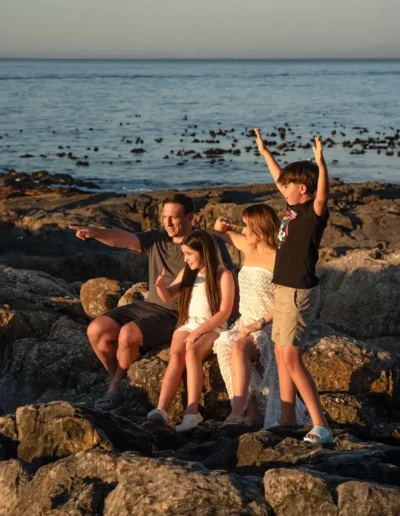 Family enjoying time together on rocks beside the ocean