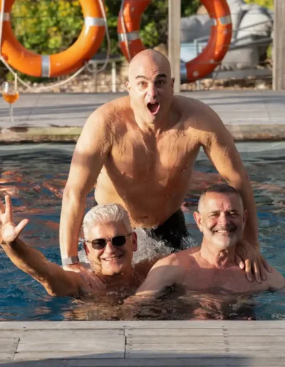 Three men smiling and having fun together in a swimming pool