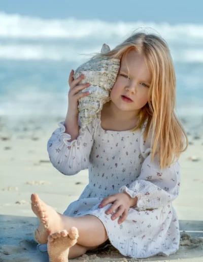 Young blonde girl holding a large seashell on a Cape Town beach