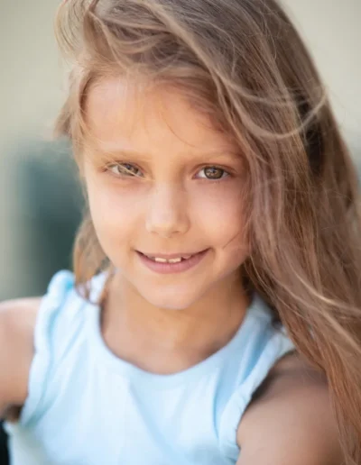 Young girl with long brown hair smiling during an outdoor portrait session