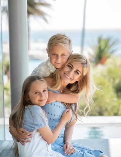 Mother hugging her son and daughter beside a swimming pool