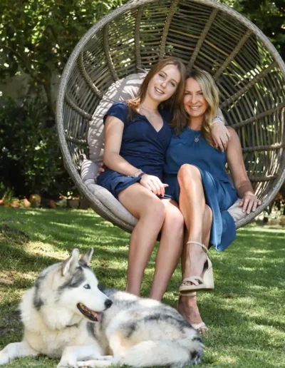 Mother and teenage daughter sitting together with their dog in a garden
