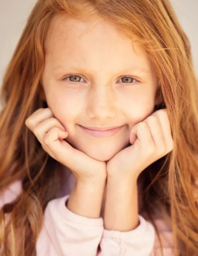 Red-haired girl smiling with her chin resting on her hands