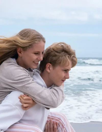 Brother carrying his sister on his back beside the ocean